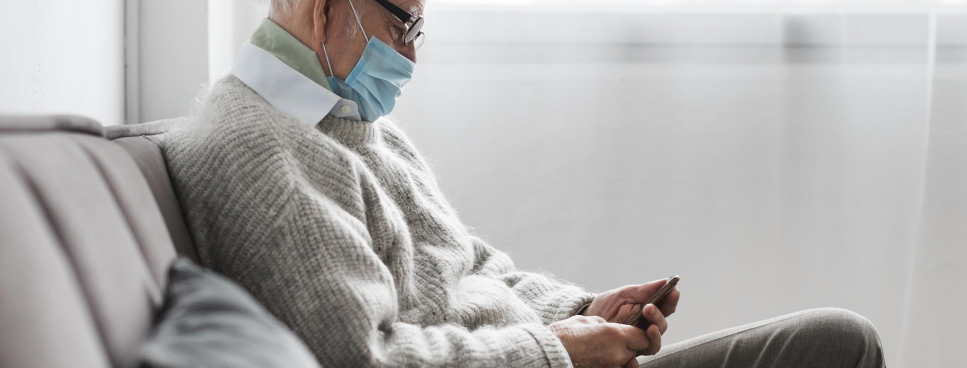 side-view-of-old-man-with-medical-mask-in-nursing-home-using-smartphone.jpg personas mayores y covid19