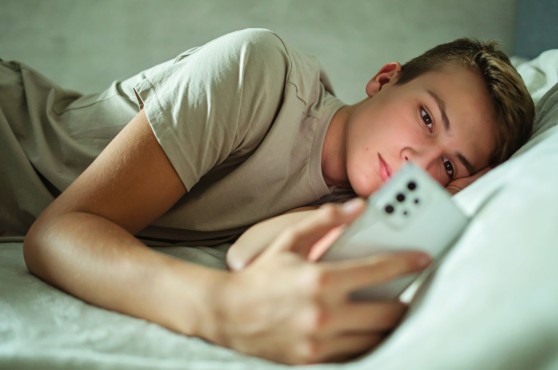 Adolescent mirant el mòbil al llit