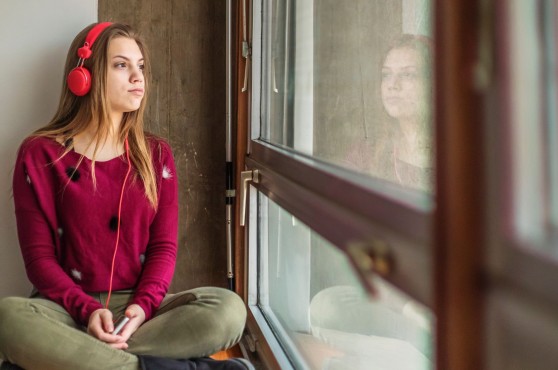 Chica con auriculares mirando por la ventana
