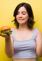 Chica dudando entre comer hamburguesa o manzana.